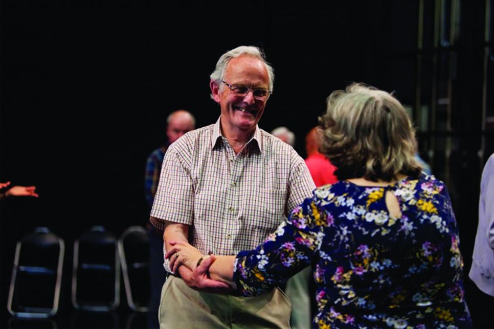 Elderly man dancing with woman hand-in-hand