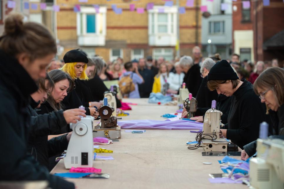 People at a long table sewing