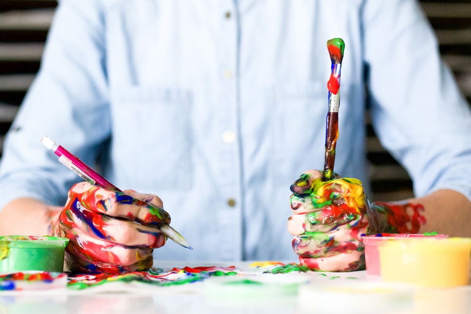 Man holding paintbrushes covered in paint