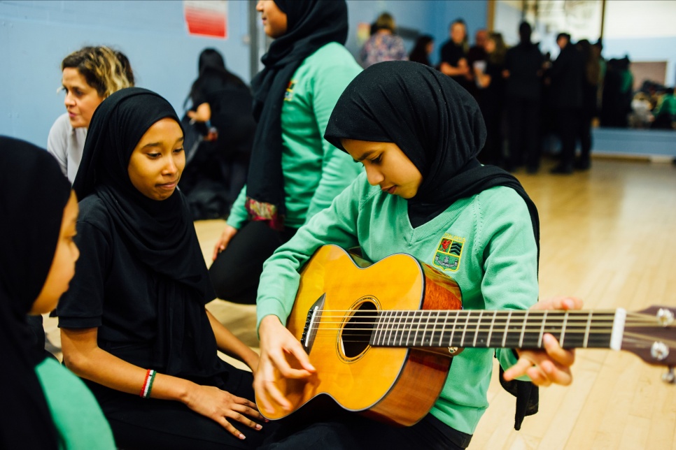 Three pupils from Fitzalan High School Cardiff, with one pupil playing a guitar