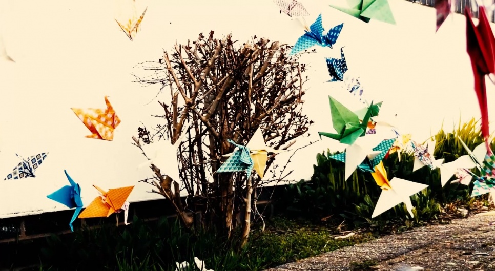Colourful origami birds flying in front of a tree