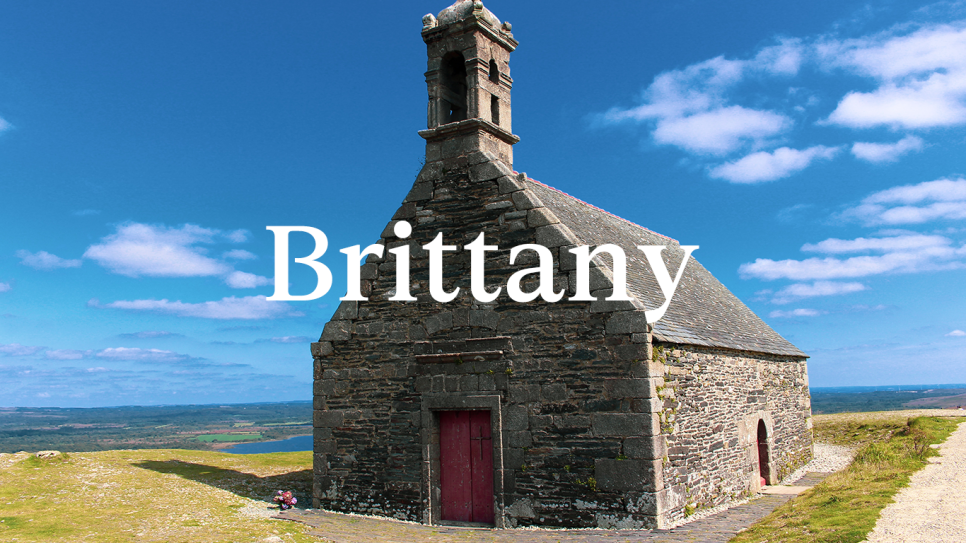 A historical church on a bright summers day with the word Brittany in white as an overlay.
