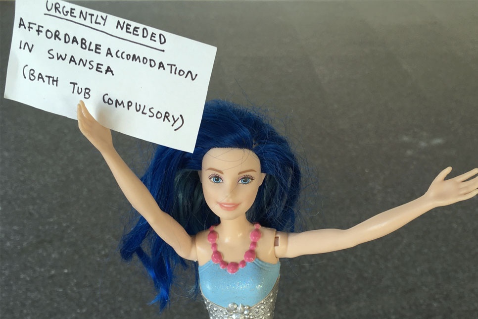 A barbie doll holding a sign