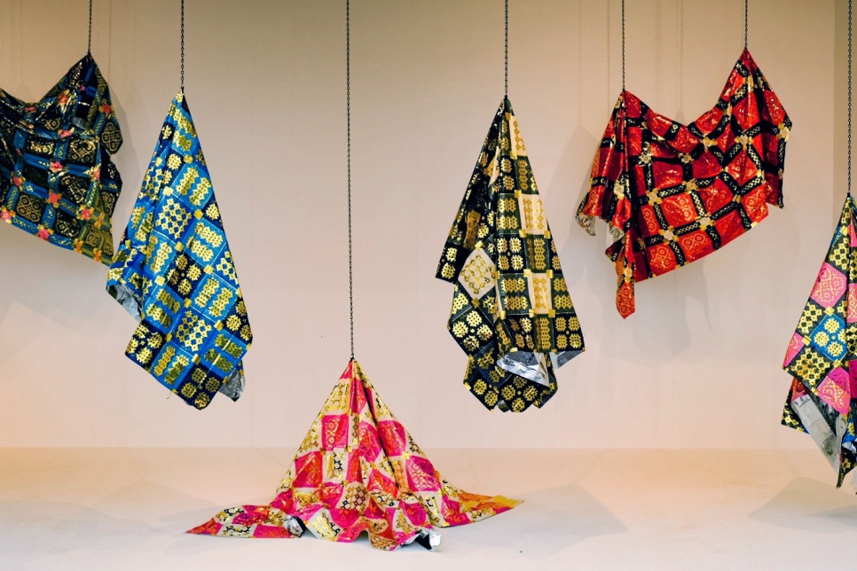 Image of multiple welsh quilts made from emergency blankets hanging from the ceiling