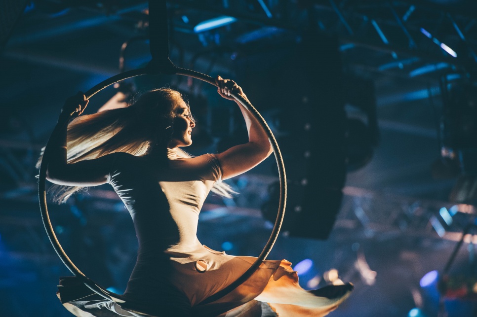 Aerial performer spinning on hoop with blue stage lighting