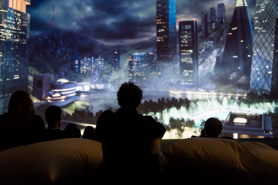 Silhouetted audience looking at large lit up cityscape image