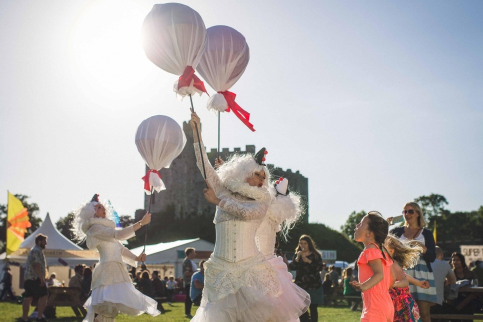 Image of three performers holding balloons with Cardiff Castle as a backdrop