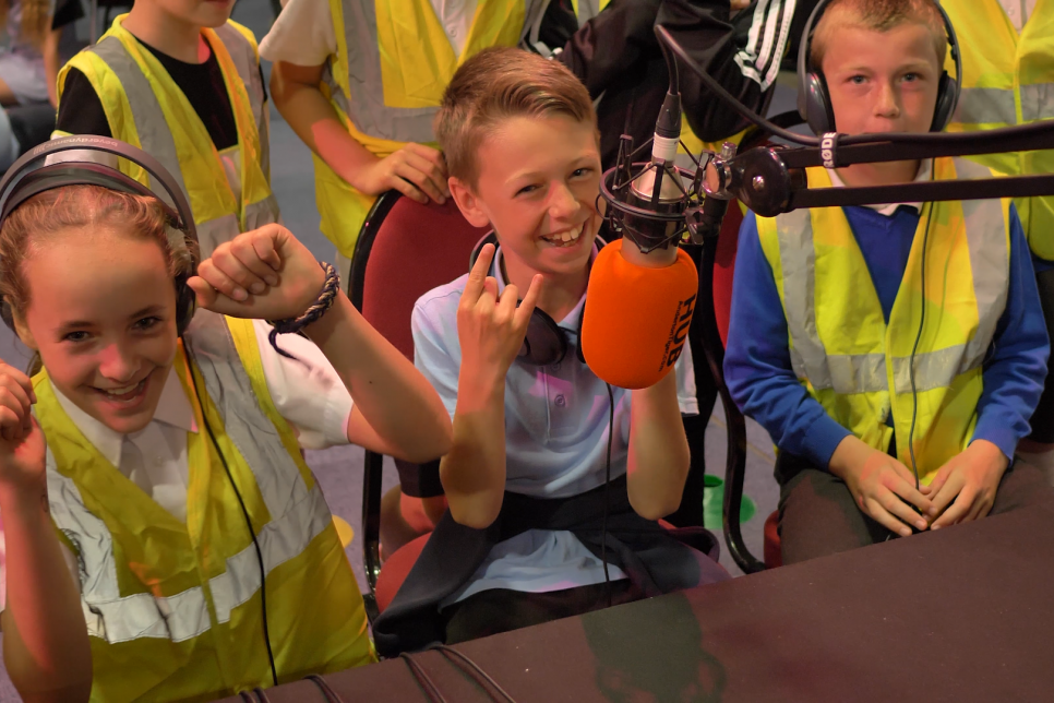 School children sat by a microphone