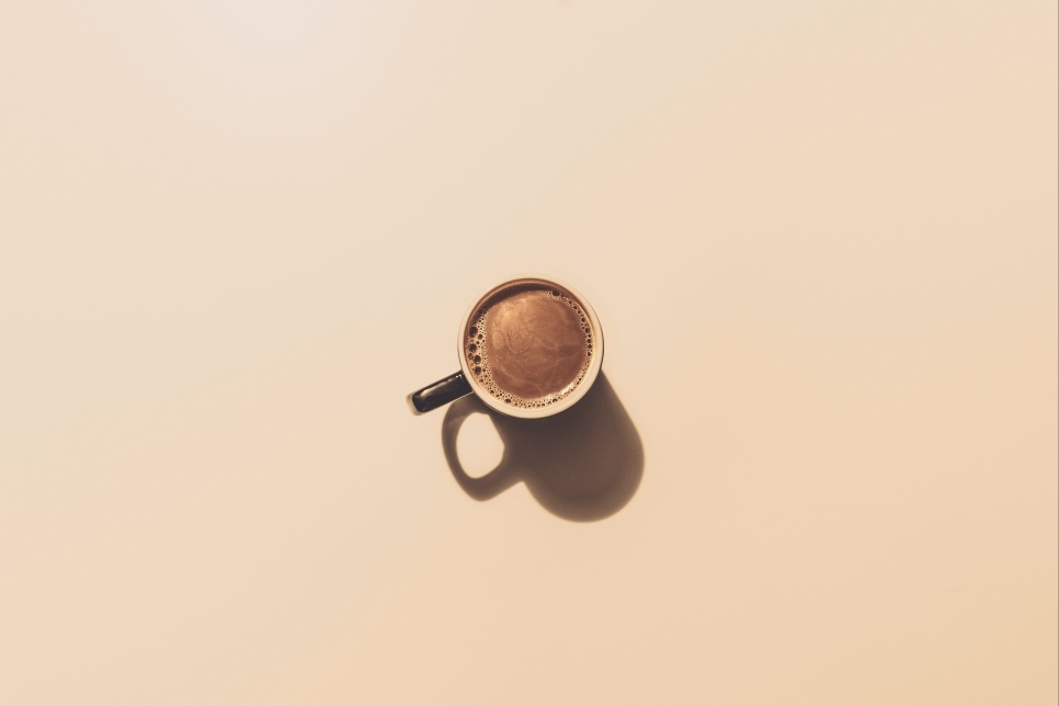 A mug of coffee in the middle of a plain beige background