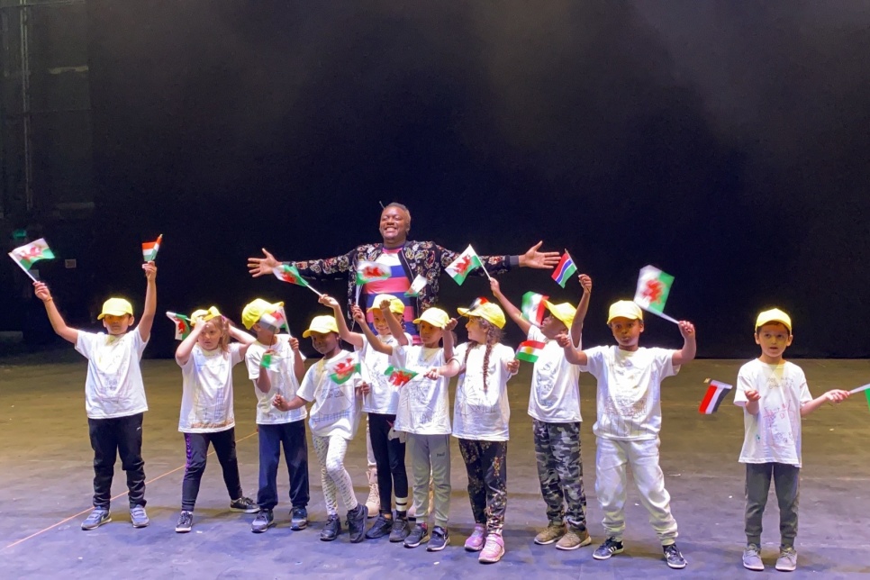 Pupils waving flags on the stage of the Millennium Centre