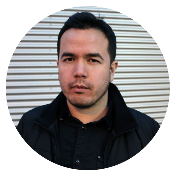 Carl Morris in a black shirt and jacket in front of a corrugated background.