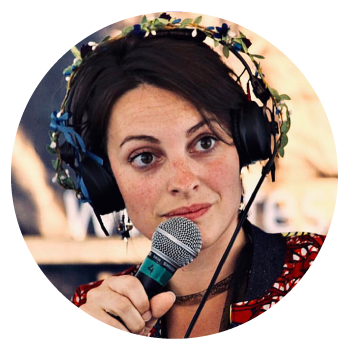 Enora Molac wearing headphones wrapped with flowers and holding a microphone.