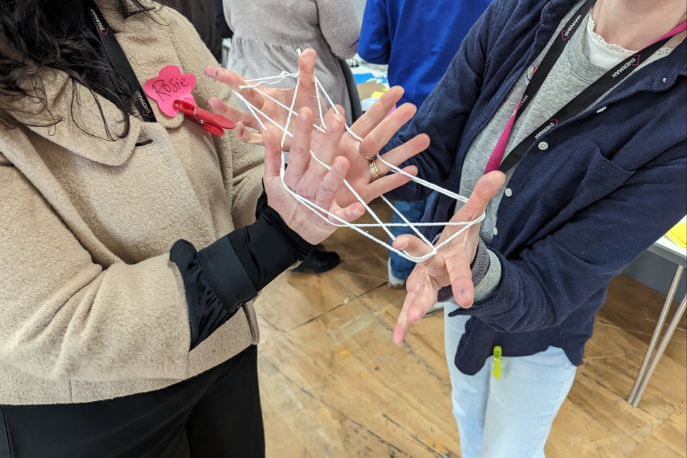 Two people with their hands entwined with string