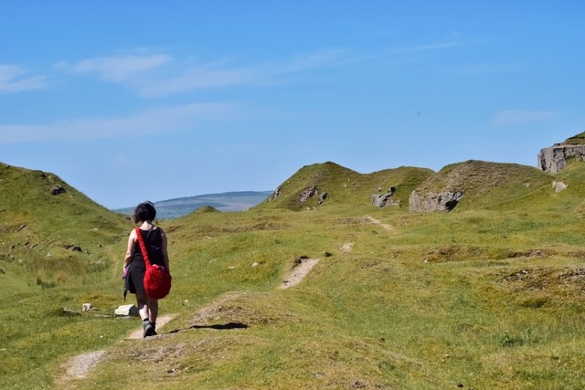 Woman walking through mountains with a blue sky in the background