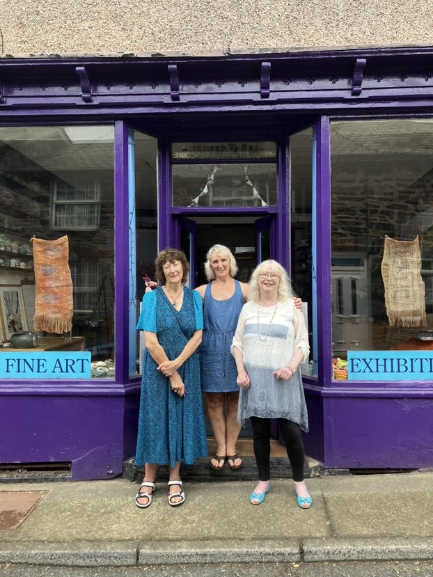 Three women stood in the doorway of a shop painted purple