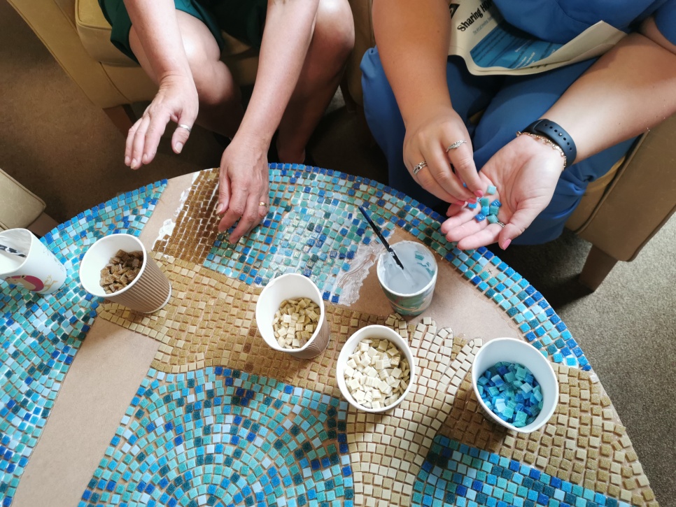 Image of a mosaic being created on a round tabletop / Delwedd o fosaig yn cael ei greu ar ben bwrdd crwn 