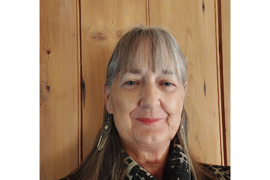 Close-up portrait of Diane Hebb, smiling against a wooden background.