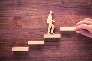 An image showing a figure walking across wooden blocks on a darker wood background