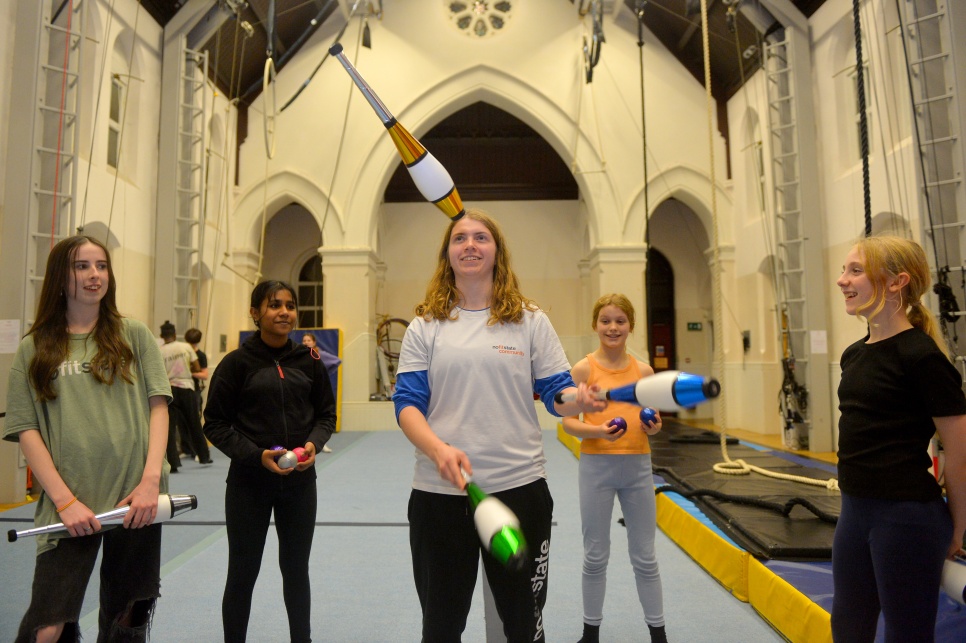a group of young people looking at a person doing some juggling
