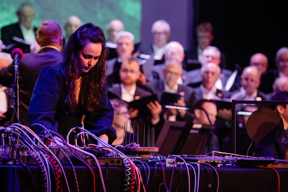Person playing an electronic music instrument with a choir in the background