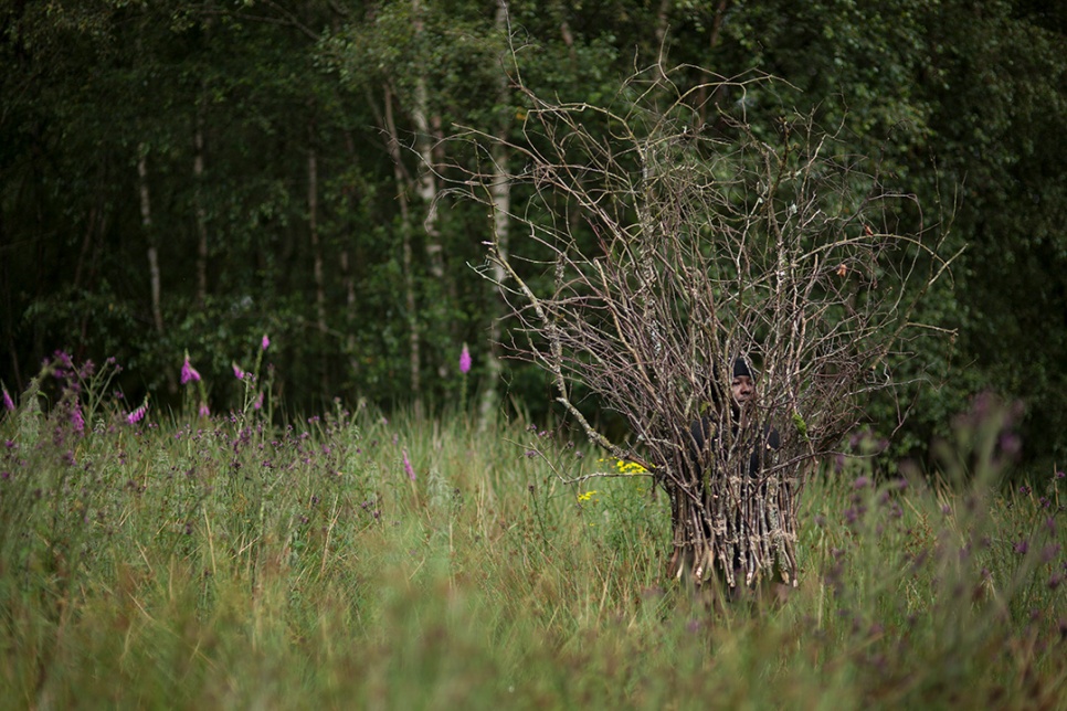 Picture of a person standing within a collection of twigs in a wildflower meadow