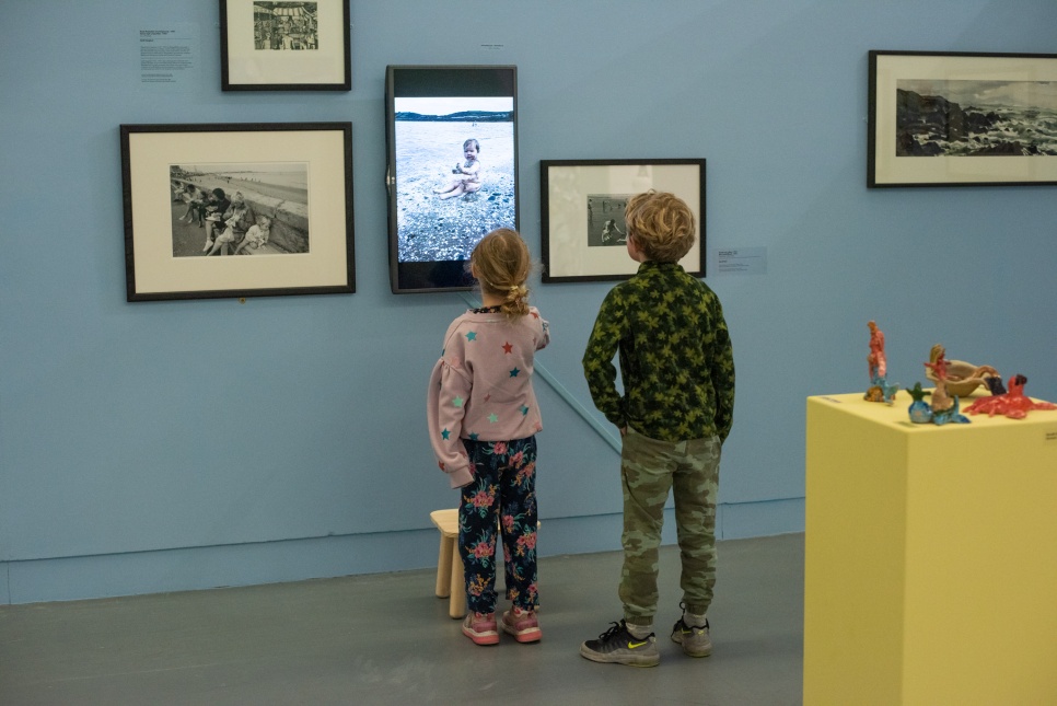 Two young children looking at artwork in a gallery