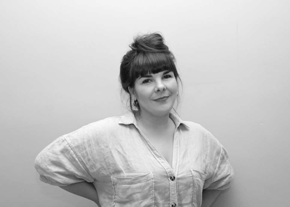 A woman smiling with hands on hips, in black and white