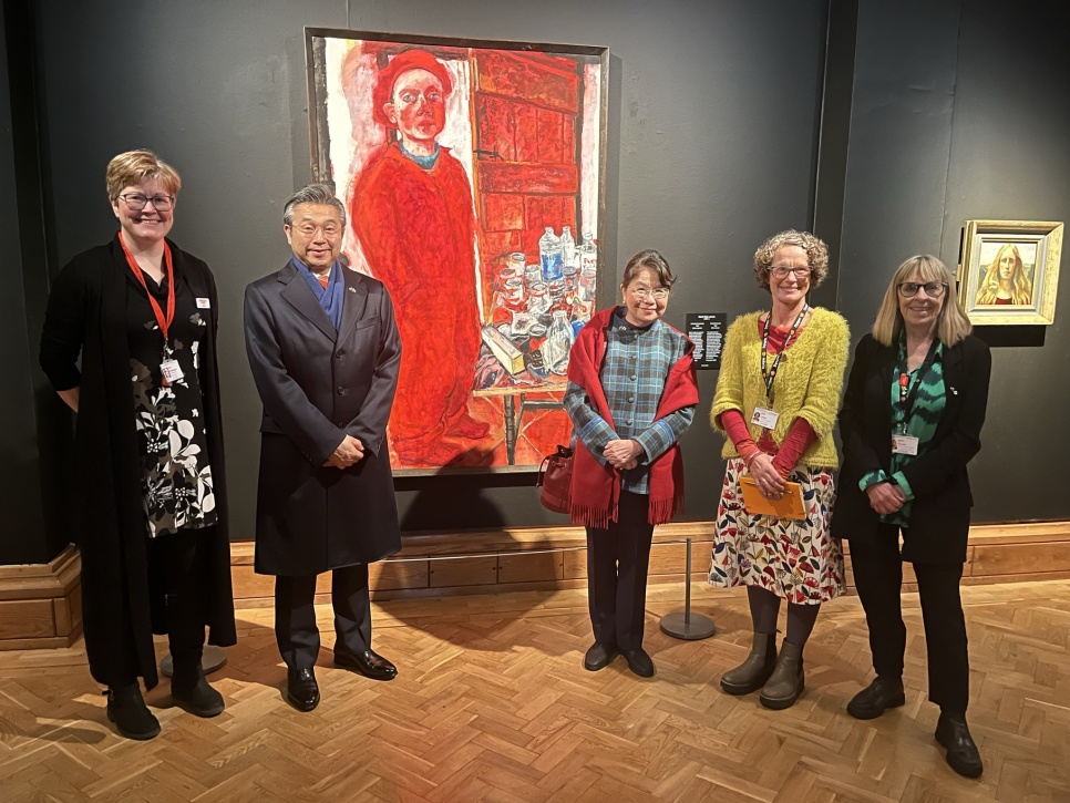 5 people smiling, stood in front of a large red portrait