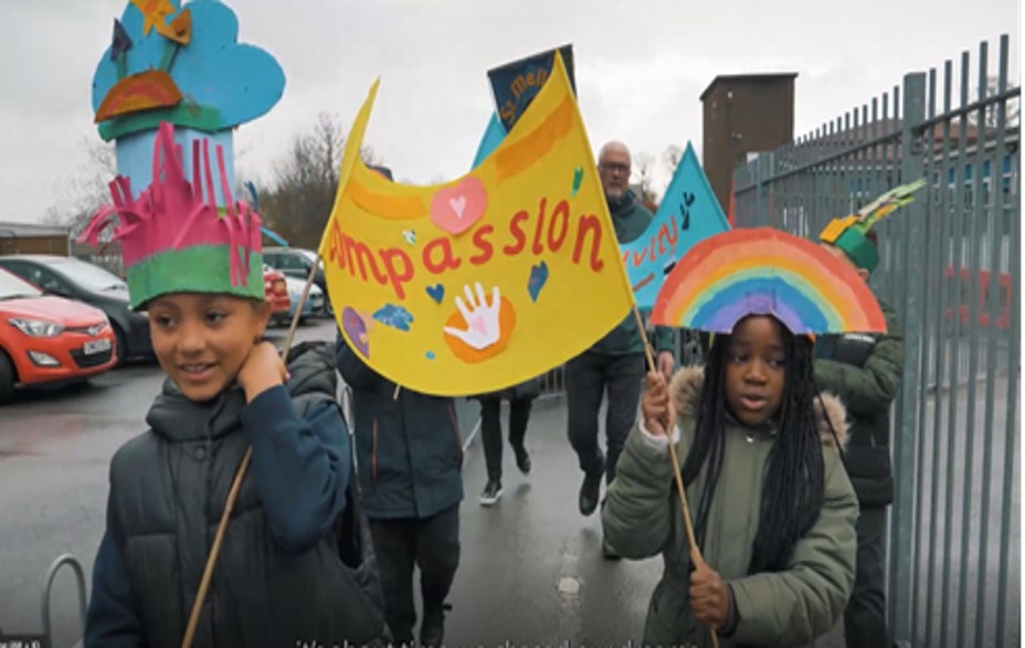 School children carrying a colourful banner