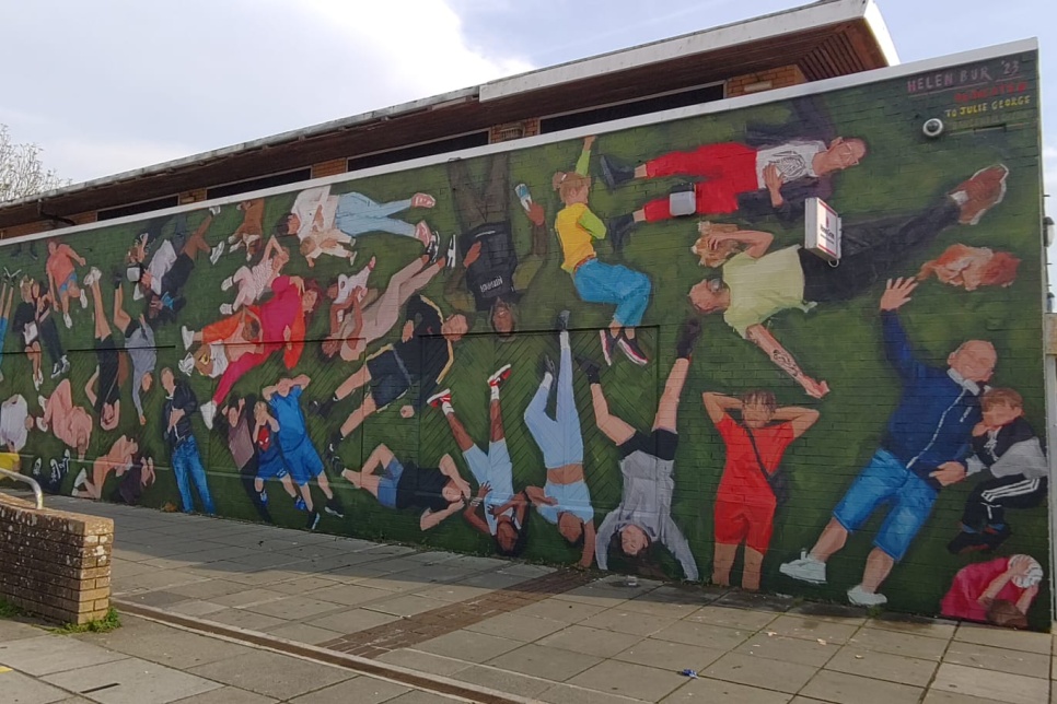 Large mural showing 50+ people and their dogs lying down in a park