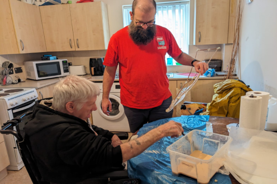 Photograph of two men in a kitchen working on an art activity / Ffotograff o ddau ddyn mewn cegin yn gweithio ar weithgaredd celf