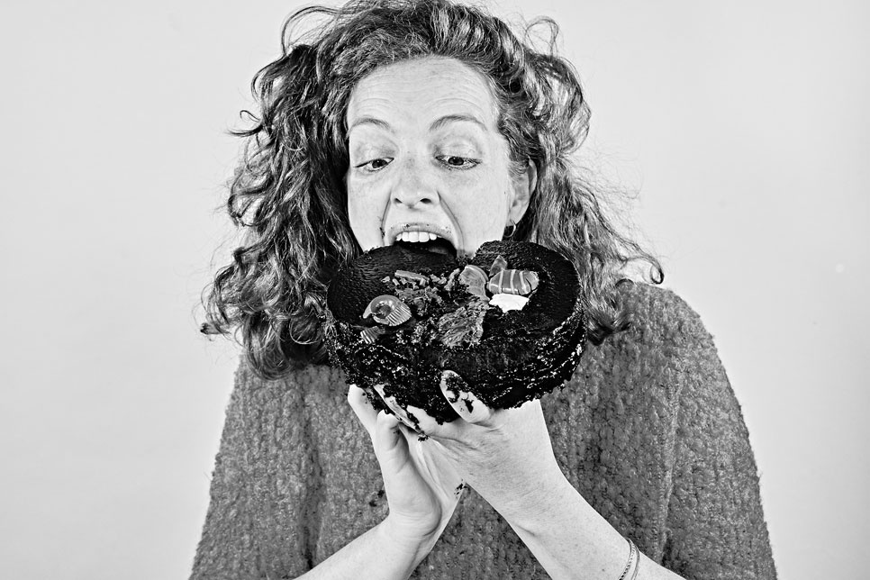 A person stuffing a huge chocolate cake into their mouths