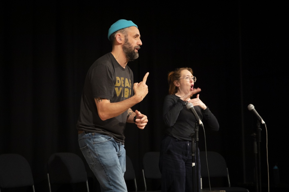 Two people on a stage using BSL / Dau berson ar y llwyfan yn defnyddio Iaith Arwyddion Prydain