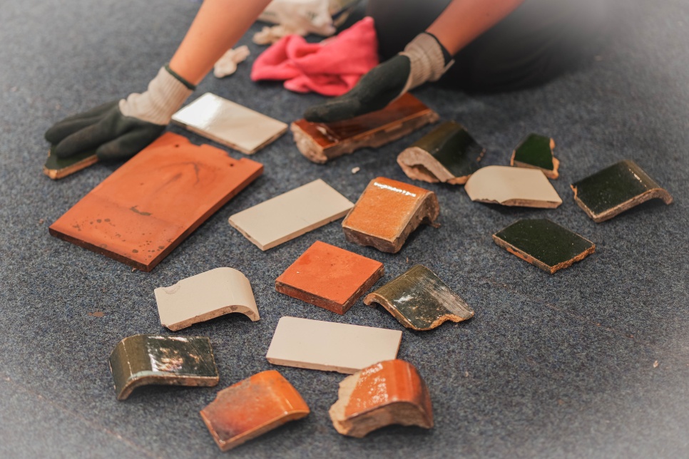 Many pieces of tiles and ceramics lying on the floor / Nifer o ddarnau teil a serameg ar y llawr