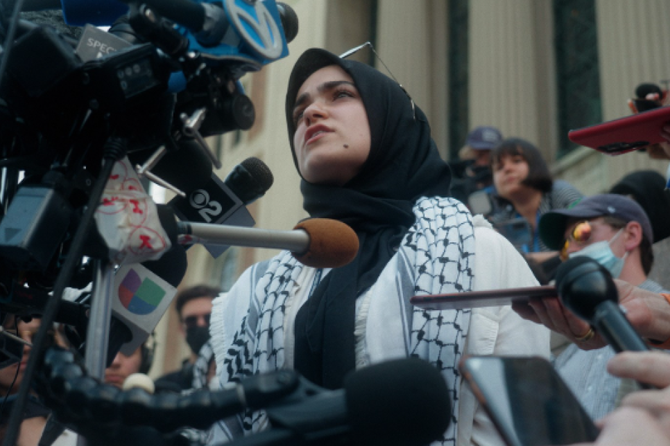 Photograph of a woman standing in front of microphones / Ffotograff o fenyw yn sefyll o flaen meicroffonau