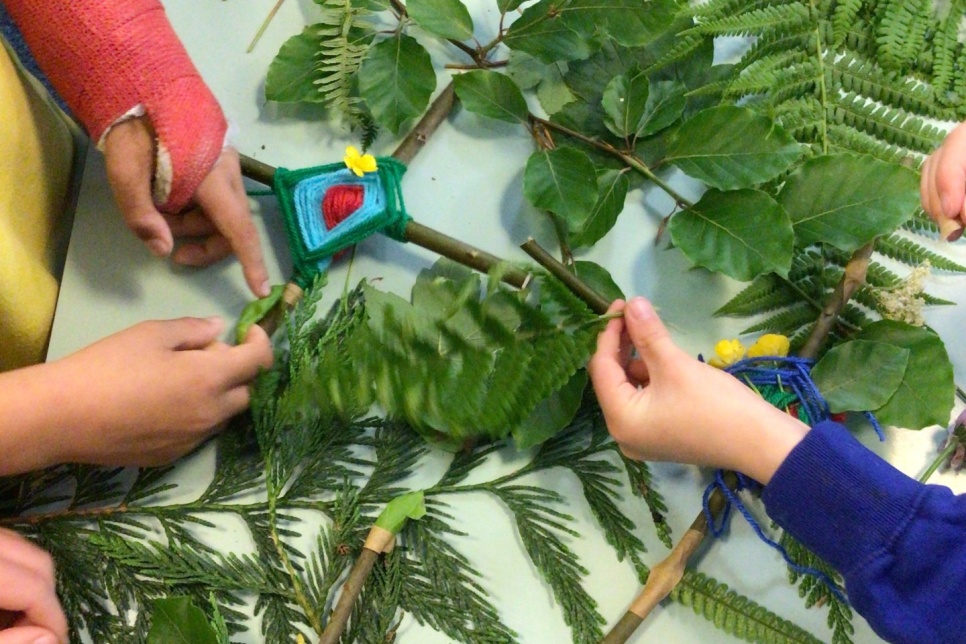 Image – pairs of hands above different types of foliage on a table as part of a craft activity / Delwedd – parau o ddwylo uwchben gwahanol fathau o ddeiliach ar fwrdd fel rhan o weithgaredd crefft  